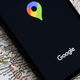 A photo of a phone opening Google Maps resting on a map.